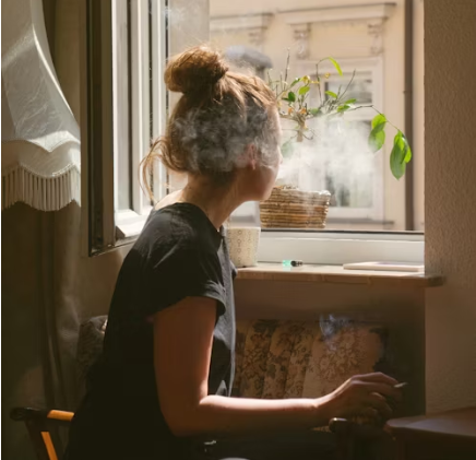 woman smoking in front of open window