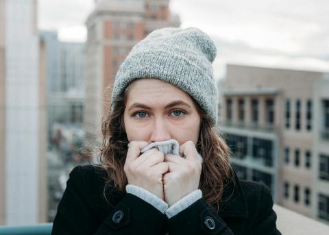 woman in a hat trying to warm up her hands